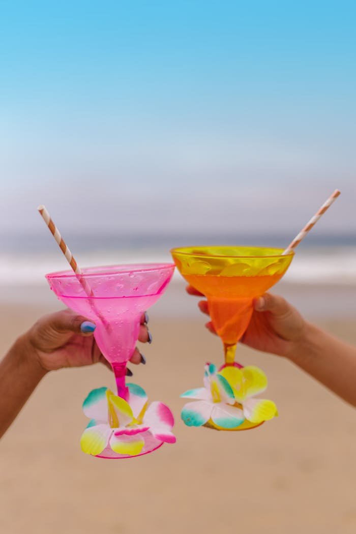 Vibrant cocktails with orchids held on a beach, symbolizing relaxation and luxury.